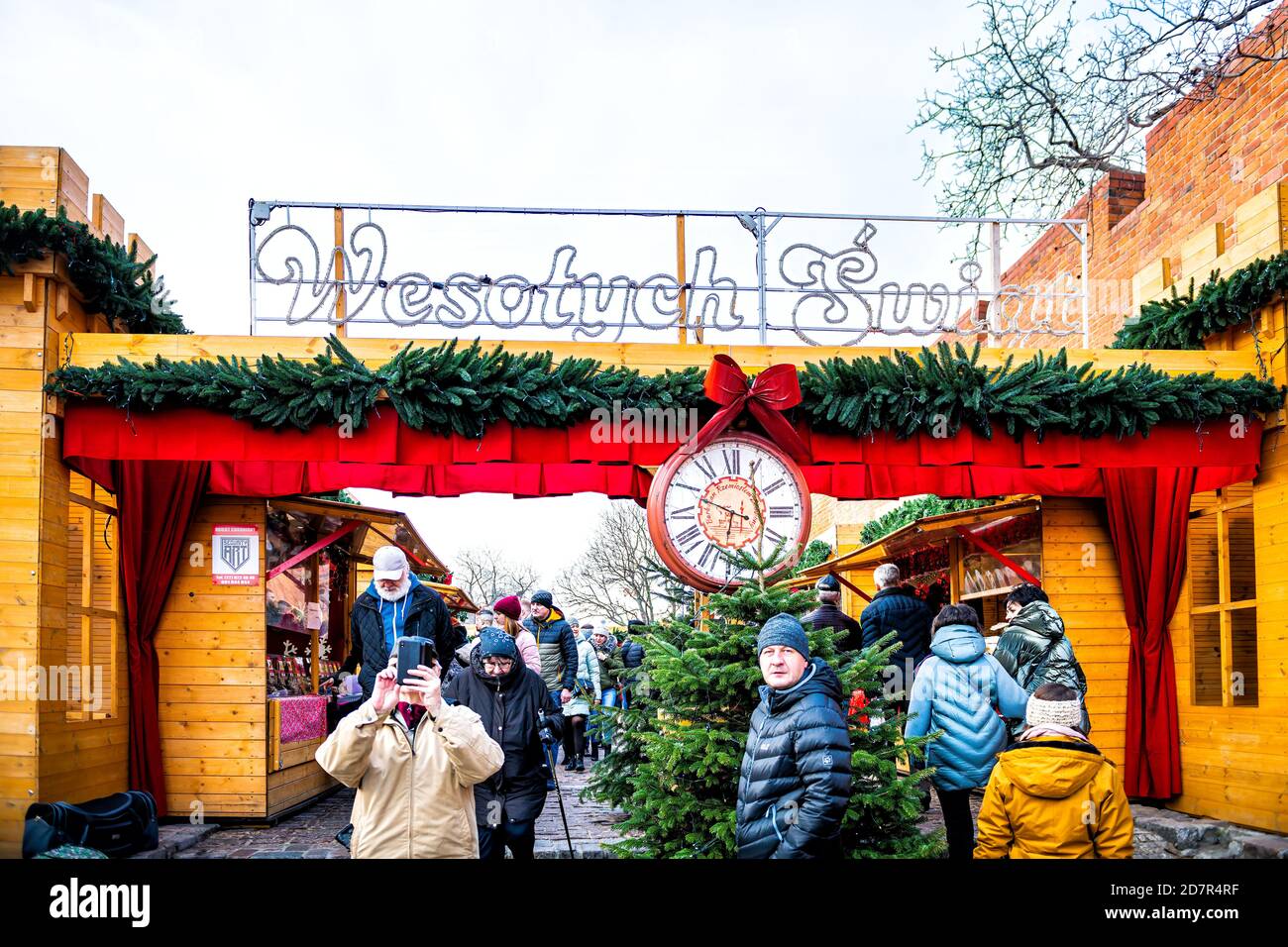 Warsaw, Poland - December 21, 2019: Old town Warszawa with Christmas market near royal castle square people walking by entrance with clock and Happy H Stock Photo
