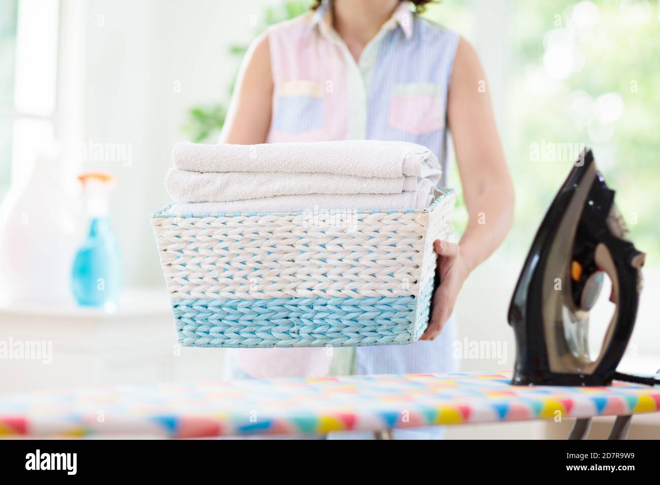 Woman ironing clothes. Female folding clothes at iron board. Home chores. Housewife cleaning house. Stock Photo