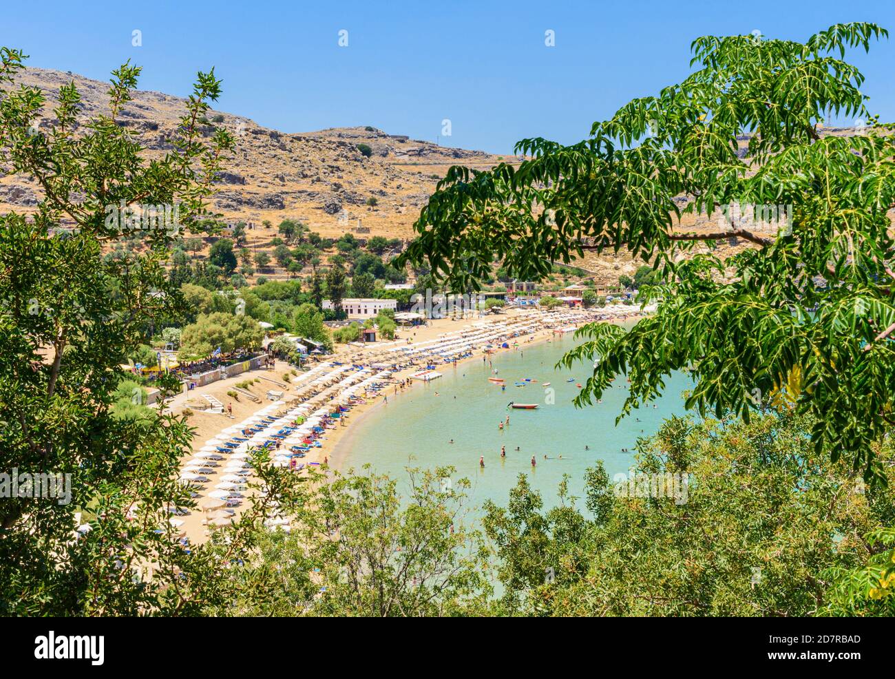 Tree framed views over Lindos Town beach, Lindos, Rhodes, Dodecanese, Greece Stock Photo