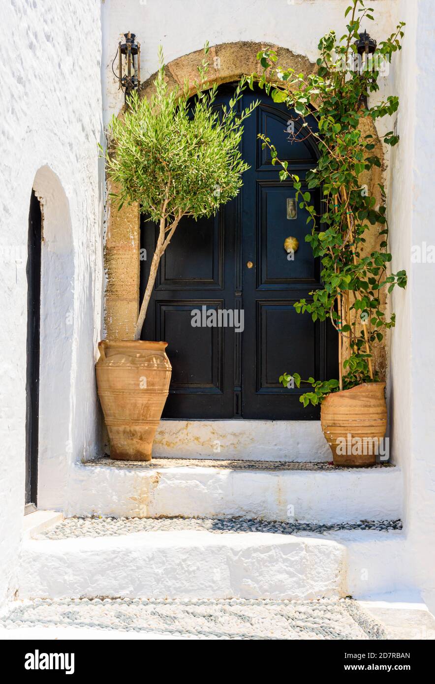 Plant pot framed large double doors in old Lindos, Rhodes, Greece Stock Photo