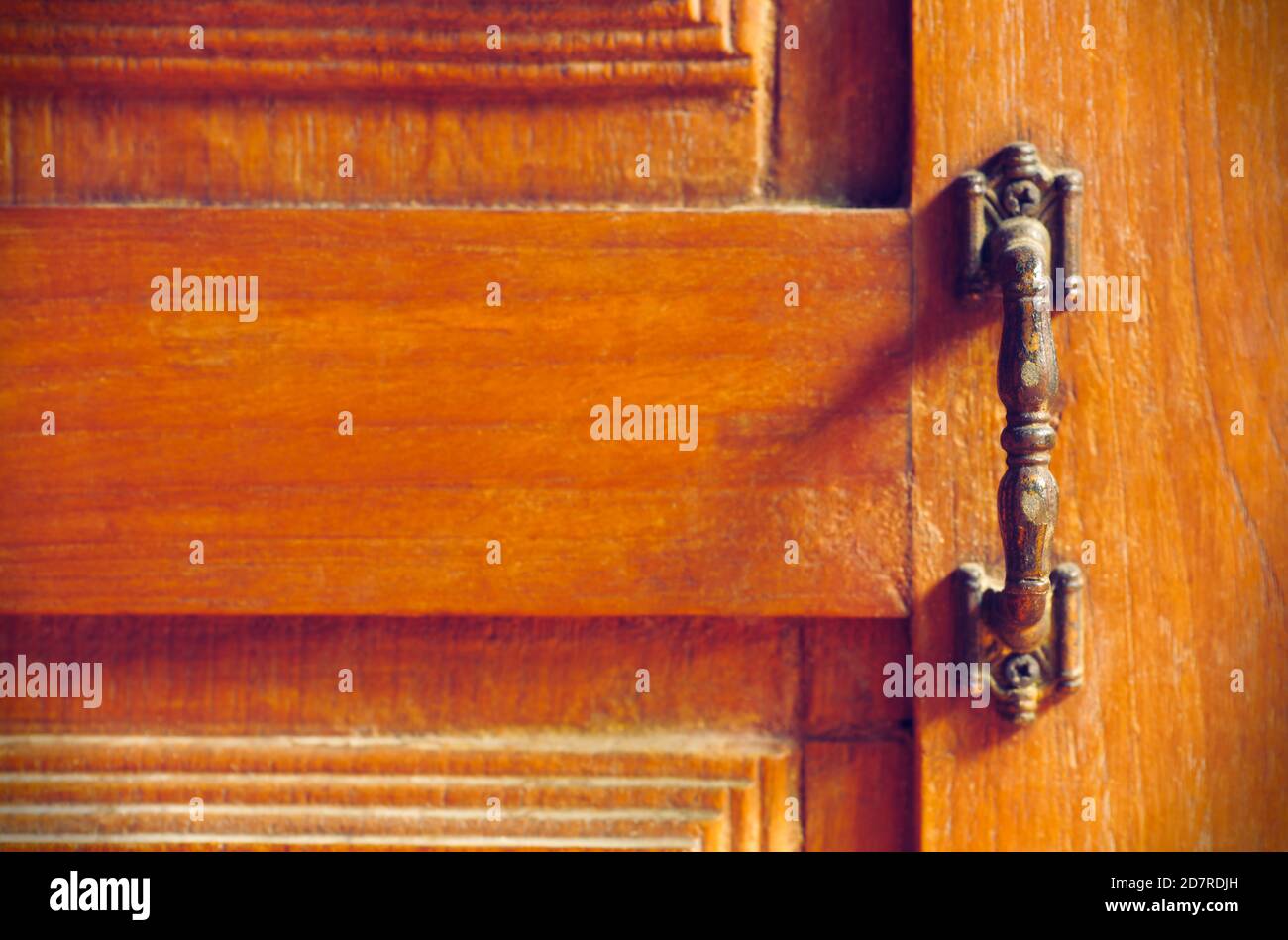 The vintage door handle on an old wooden door background and lighting and shadow in the morning. Closeup and copy space on the left. The concept of ar Stock Photo