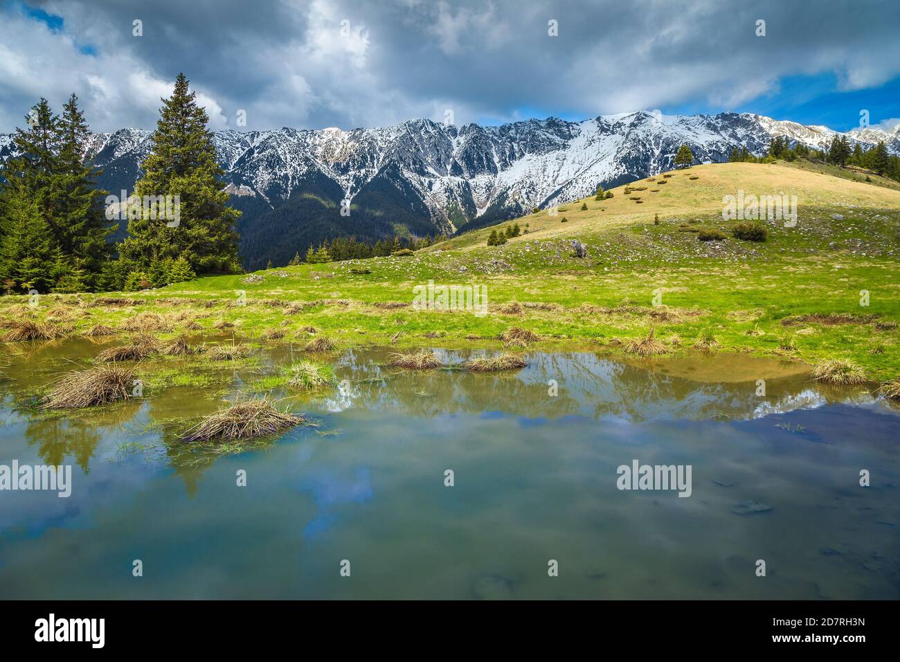 Amazing alpine landscape with small lake and high snowy Piatra Craiului mountains, near Pestera village, Transylvania, Romania, Europe Stock Photo