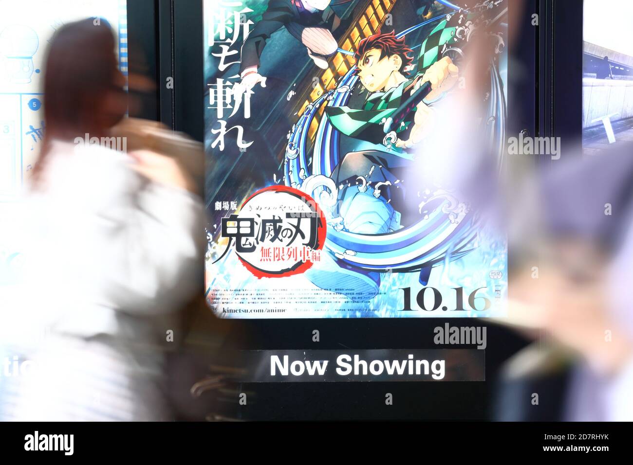 People walk past a poster for an animated film based on popular Japanese manga 'Demon Slayer: Kimetsu no Yaiba the Movie: Infinite Train' on display outside a movie theater in Tokyo, Japan on October 23, 2020. Credit: Naoki Nishimura/AFLO/Alamy Live News Stock Photo