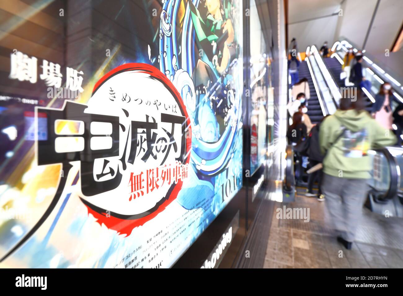 People walk past a poster for an animated film based on popular Japanese manga 'Demon Slayer: Kimetsu no Yaiba the Movie: Infinite Train' on display outside a movie theater in Tokyo, Japan on October 23, 2020. Credit: Naoki Nishimura/AFLO/Alamy Live News Stock Photo