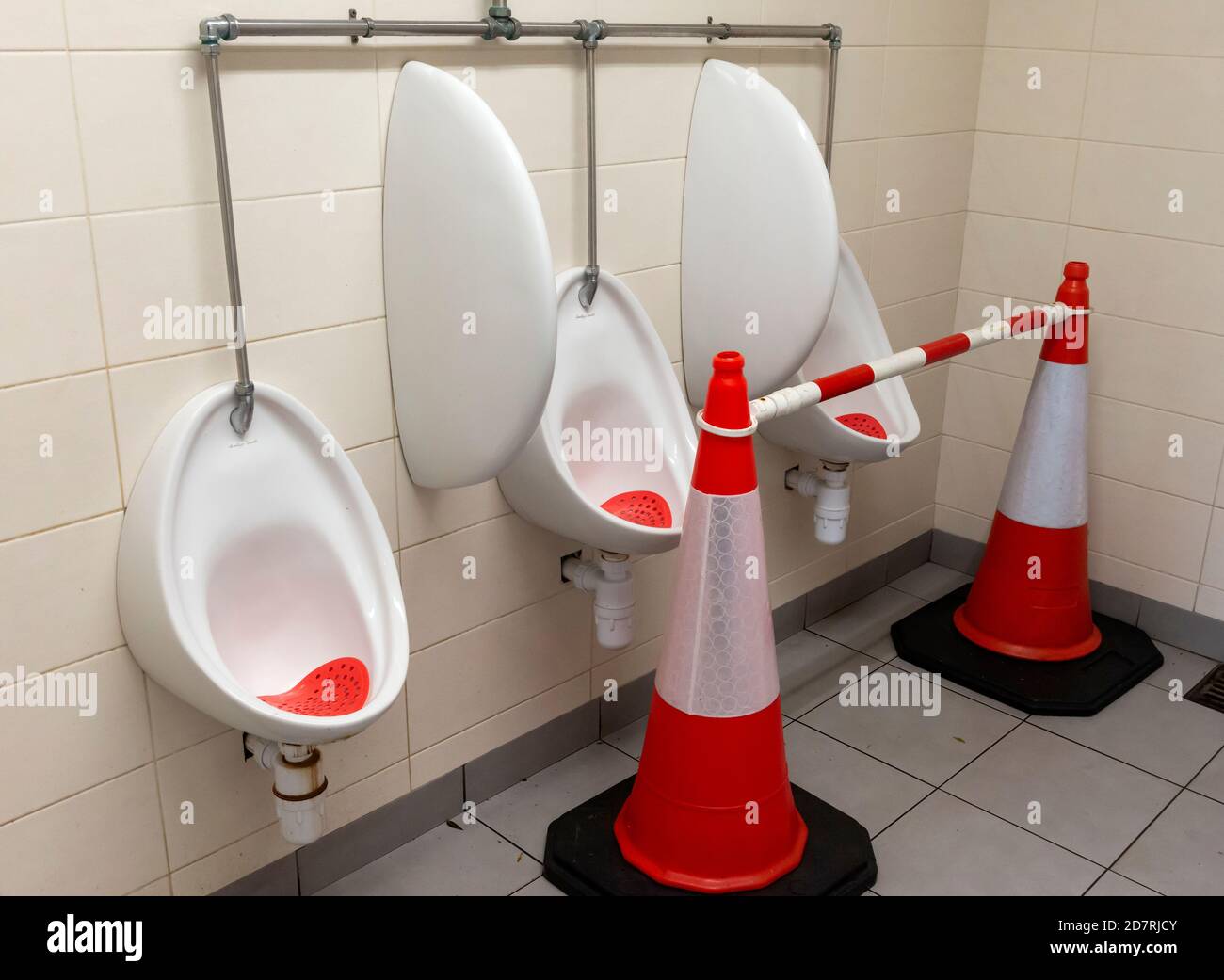 Orange traffic cones in men's gents restroom public toilet and urinals not in use for social distancing due to Covid 19 pandemic outbreak in Ireland Stock Photo