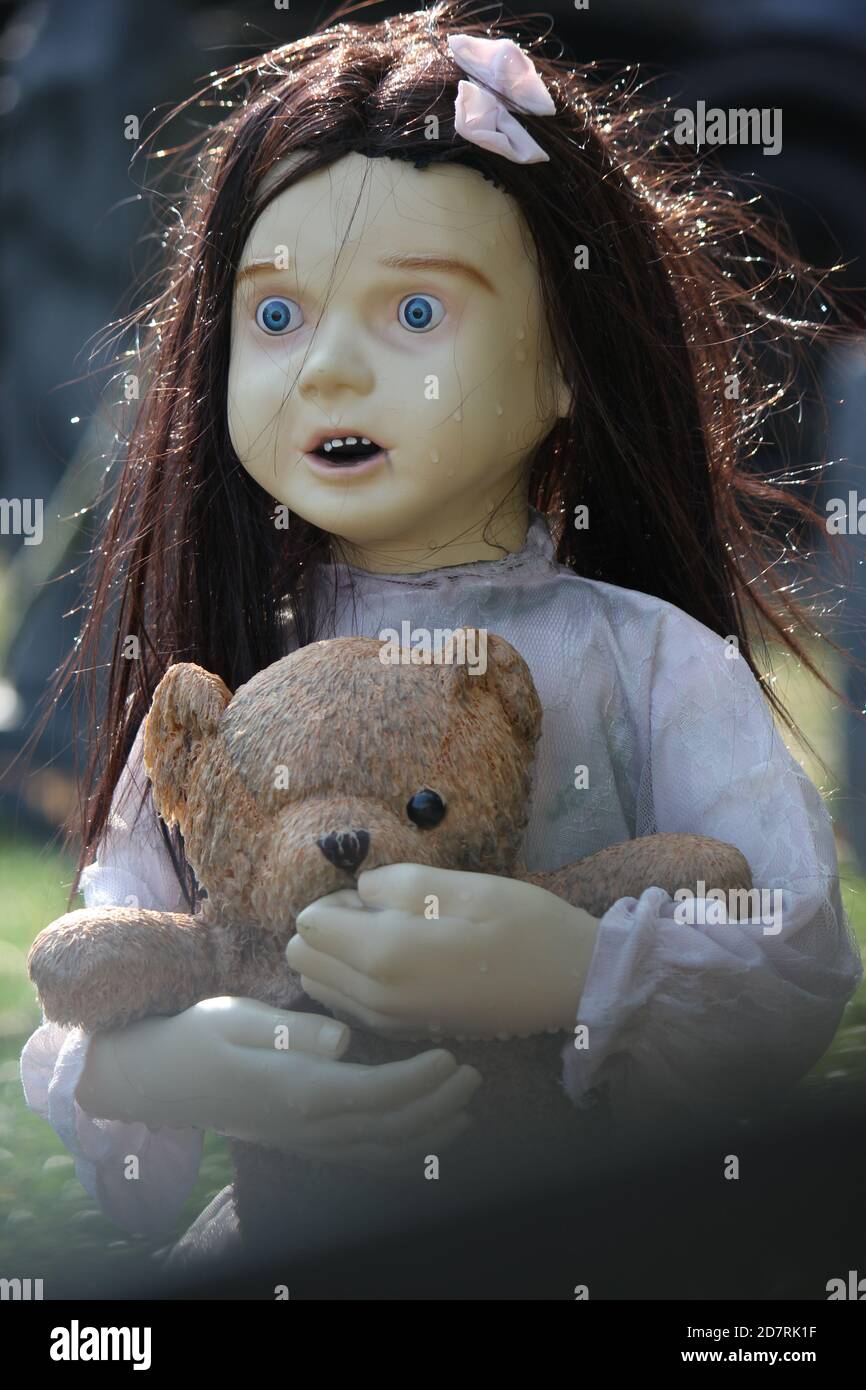 Halloween decoration of a doll of a very scared girl wearing her pajamas and clutching her teddy bear. Stock Photo