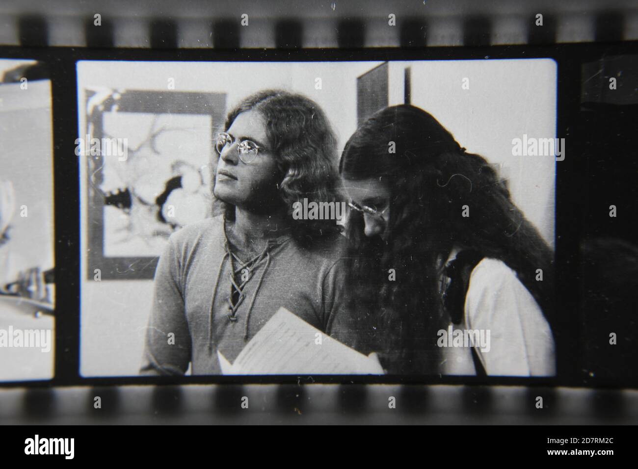 Fine 1970s vintage black and white photography of two hippies listening intently  to the announcements. Stock Photo