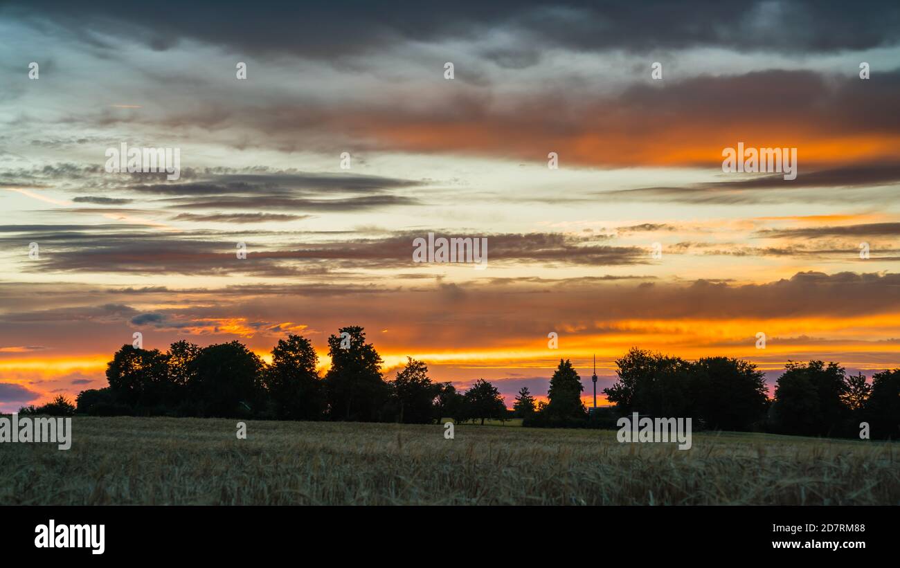 Germany, Stuttgart, Dramatic red glowing sunset sky above fields and tv ...