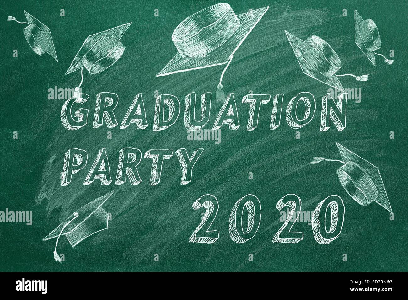 Hand drawing text 'Graduation party 2020' and graduation caps  on green chalkboard. Stock Photo