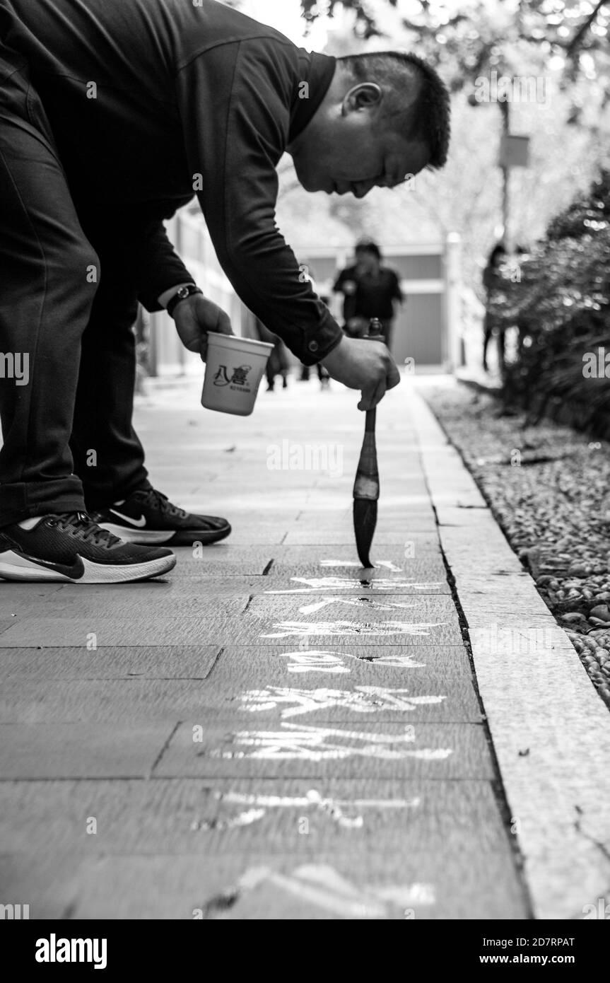 A man writes calligraphy using a water brush in Shanghai’s People’s Square. Stock Photo