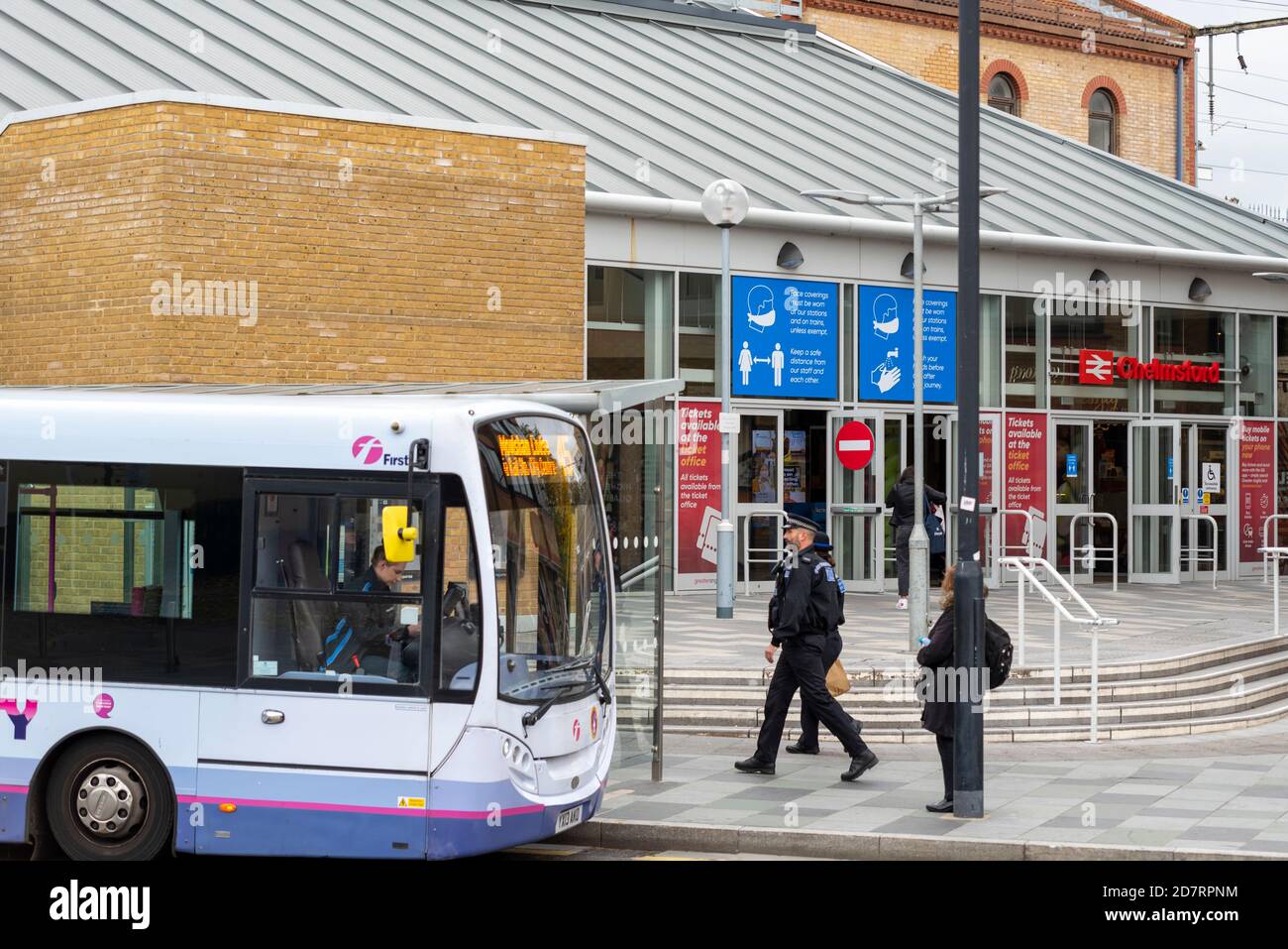 FirstGroup, FirstBus, First bus outside Chelmsford railway station, Essex, UK. Transport hub. Police officer and COVID 19 health warnings Stock Photo