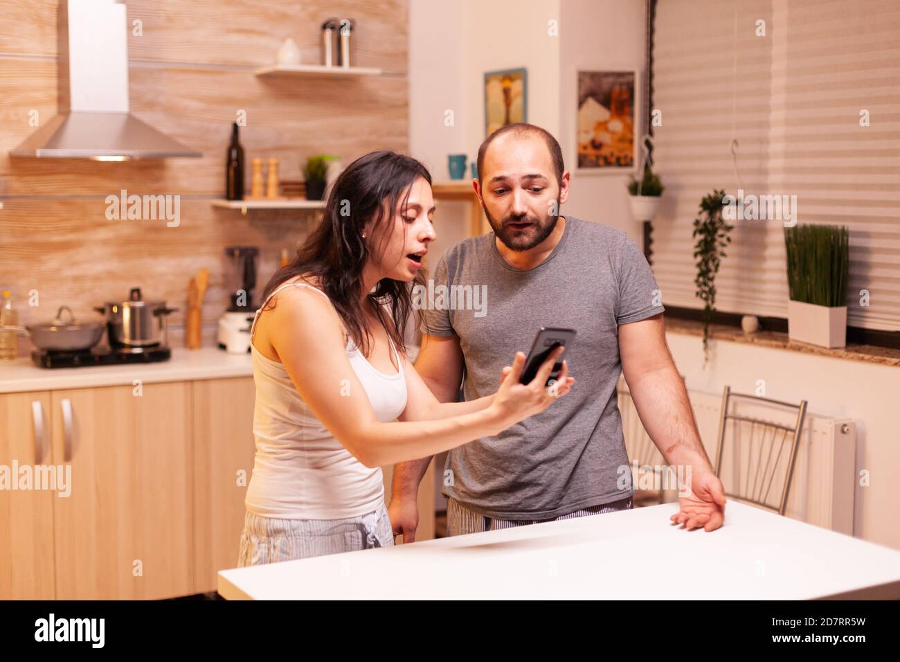 Jealous wife having nervous breakdowns because of husband. Annoyed woman cheated angry frustrated offended irritated accusing man of infidelity showing him messages on smartphone yelling desperate. Stock Photo