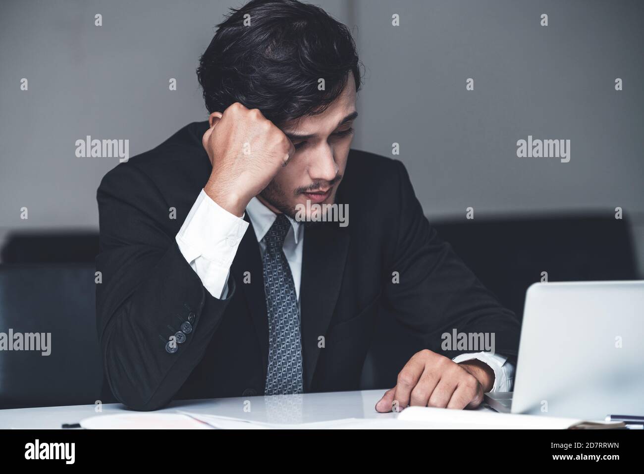 Unhappy young man, businessman feels stress at the office because of economic crisis and awful company loss. Business failure concept. Stock Photo
