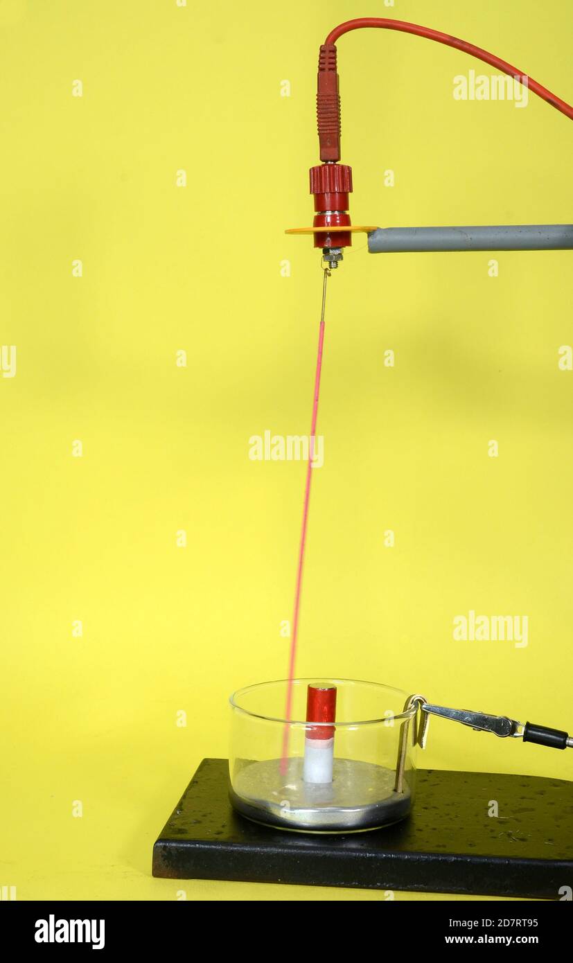 Closeup on Faraday motor demonstration arrangement with mercury pool and a light red conducter that moves in circles around a magnet when a current fl Stock Photo