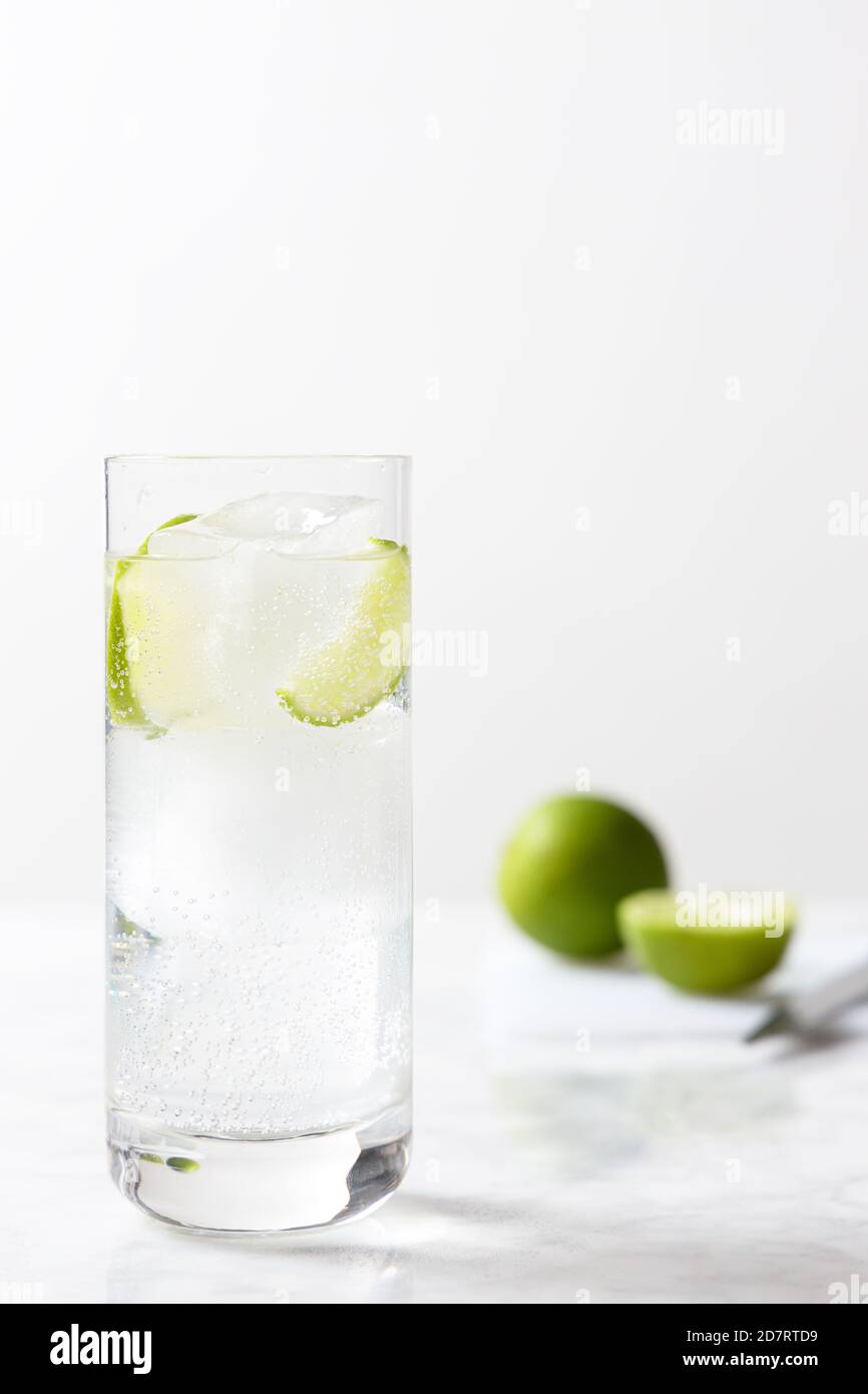 Gin tonic glass with ice cubes and lime slices. Gin tonic preparation Stock Photo