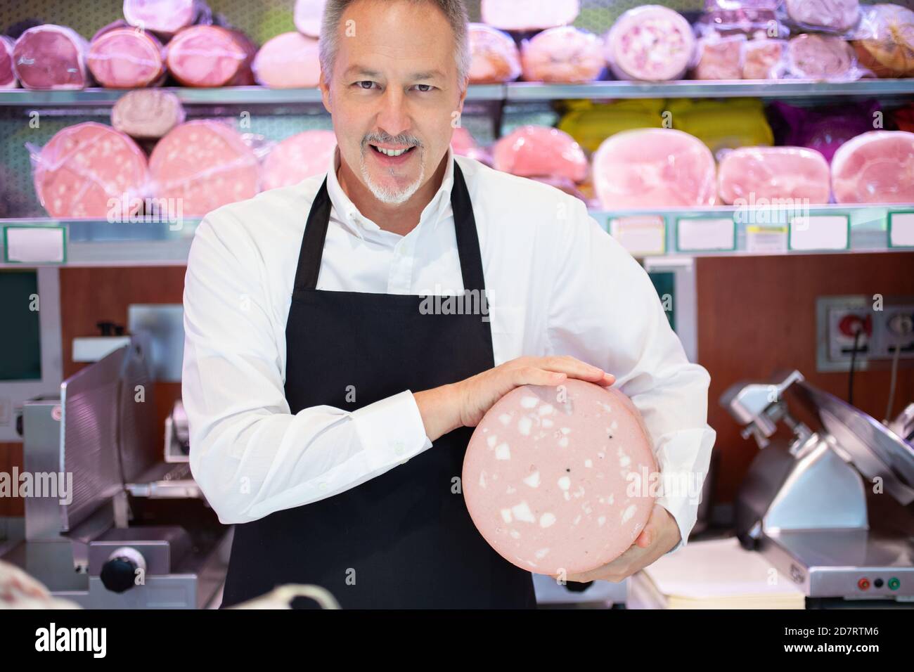 Shopkeeper showing a bologna in an italian grocery store Stock Photo