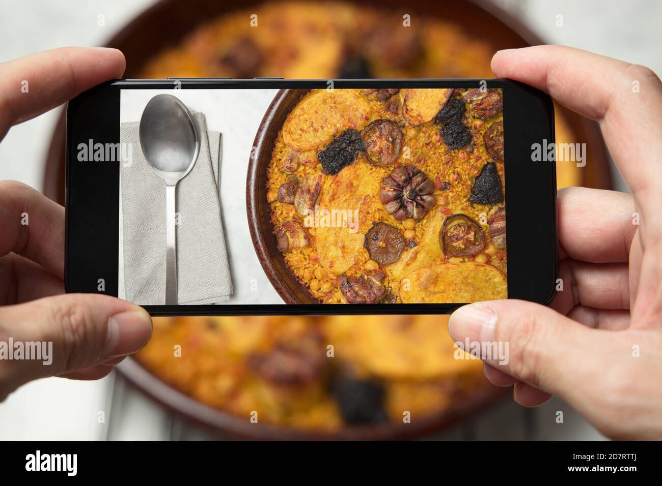 Man's hands taking a picture of a baked rice casserole. Valencia, Spain Stock Photo