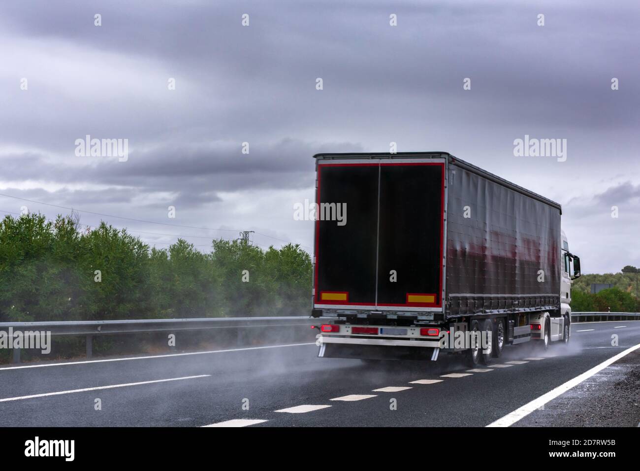 Truck with a black semitrailer driving on a day with bad weather due