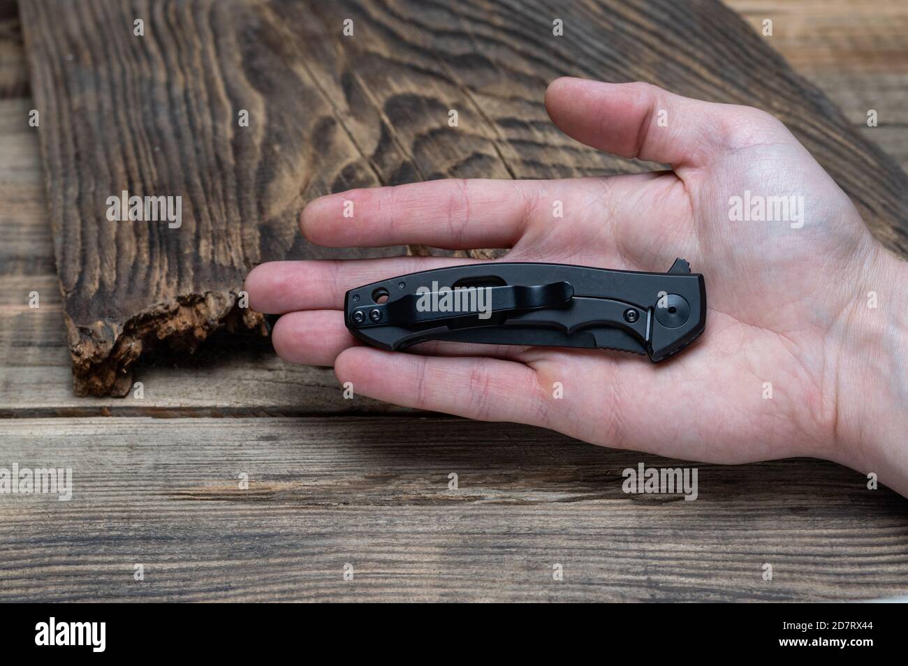 The reverse side of the knife with a clip and a side lock. Small knife in the palm. Front view. Stock Photo