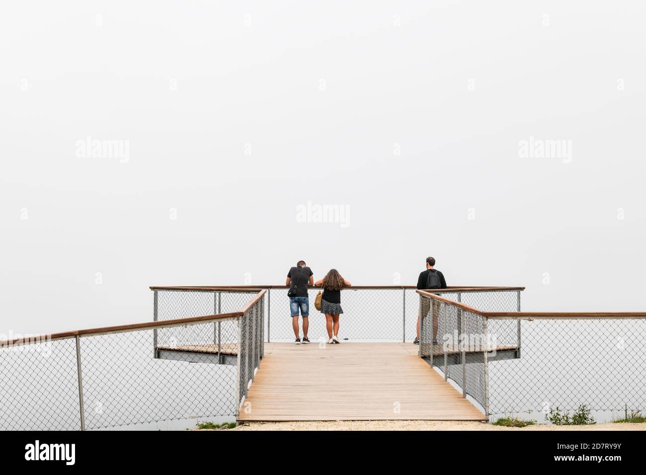 PONTEVEDRA, SPAIN - AUGUST 25, 2020: A small group of people wait for the fog to rise on a modern lookout over the Ria de Arousa estuary in Galicia. Stock Photo