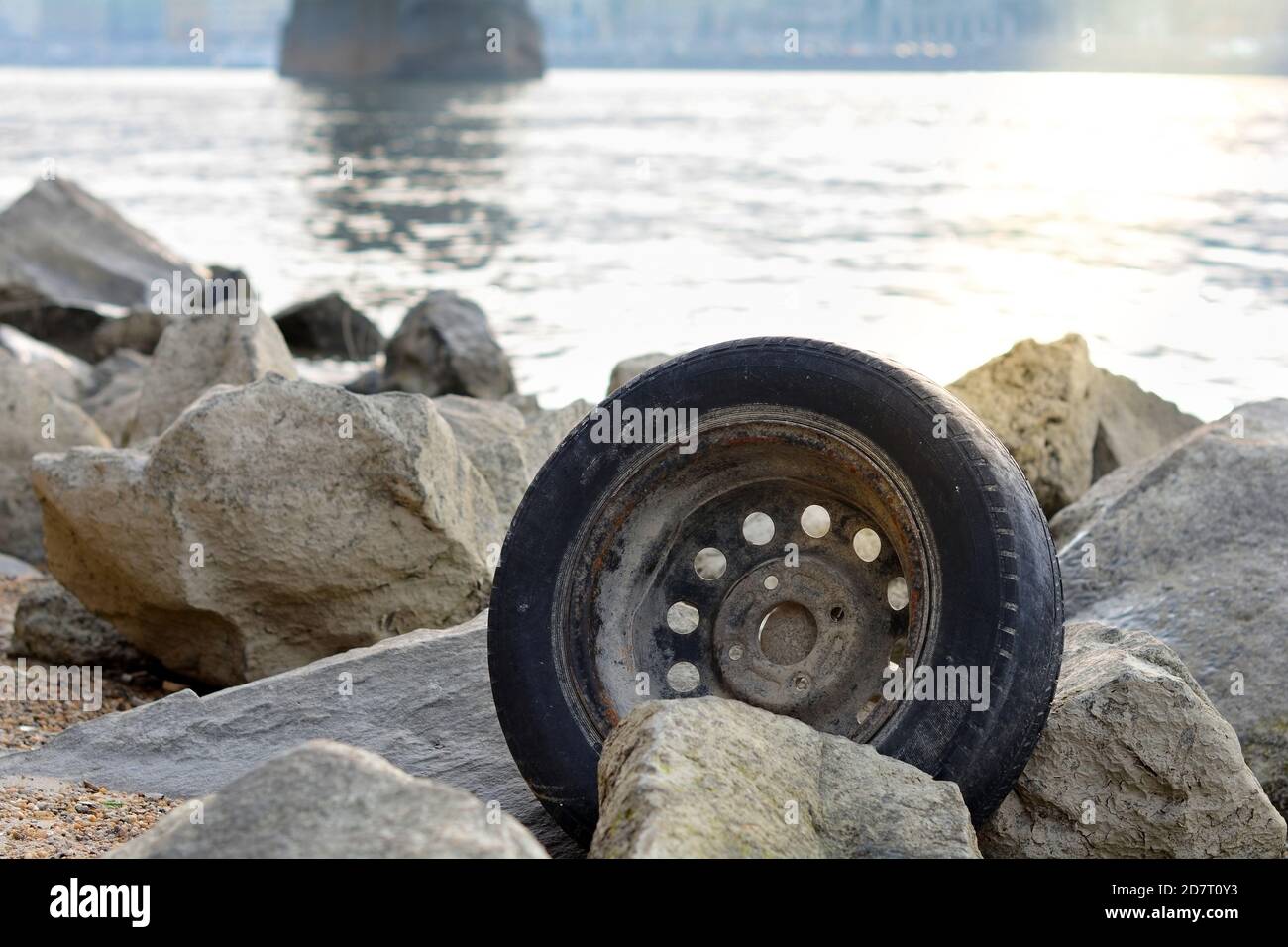 Abandoned and used wheel tire on the coastline. The problem of waste