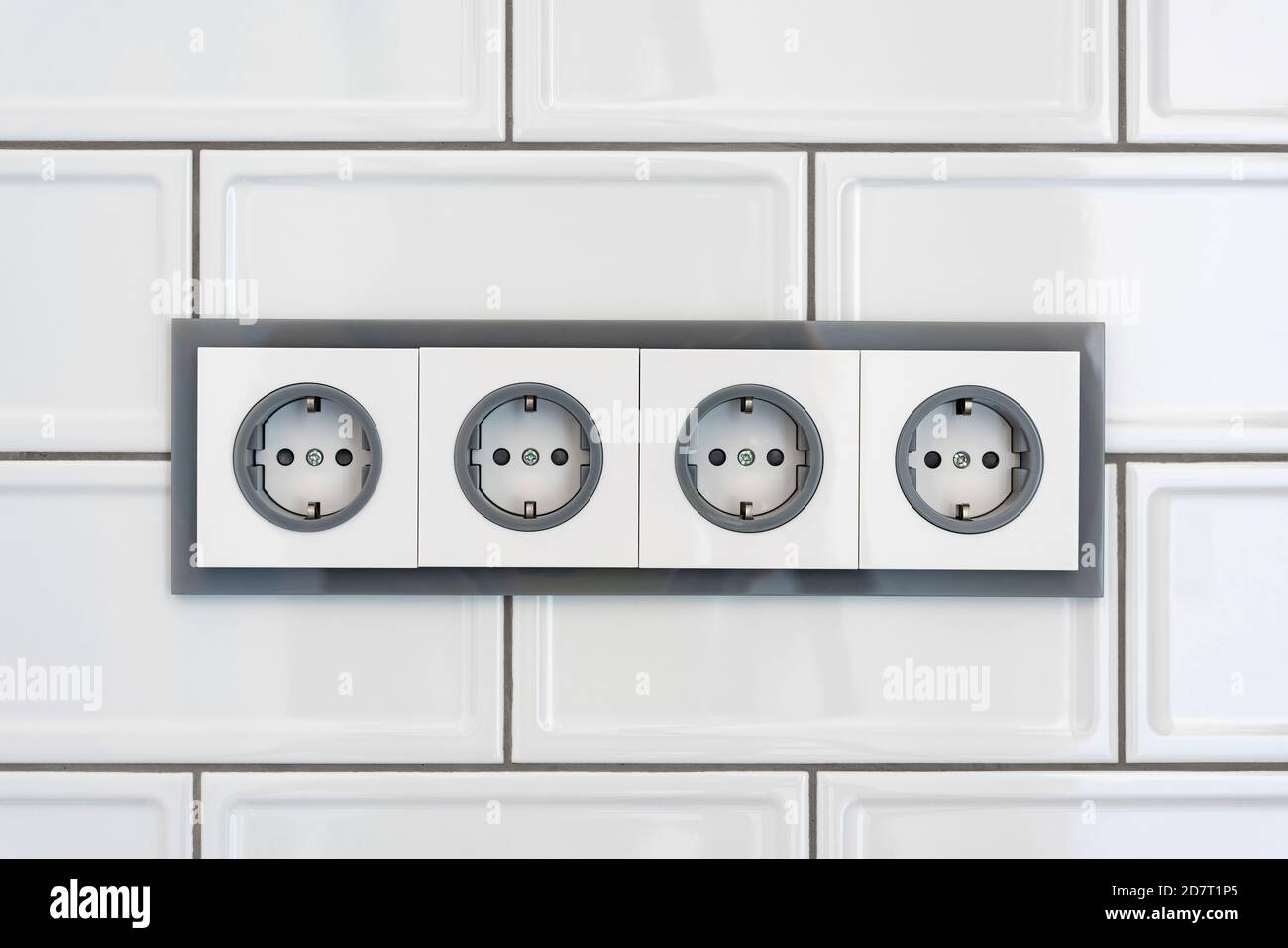Installation modern sockets on a tile wall closeup. Grey and white
