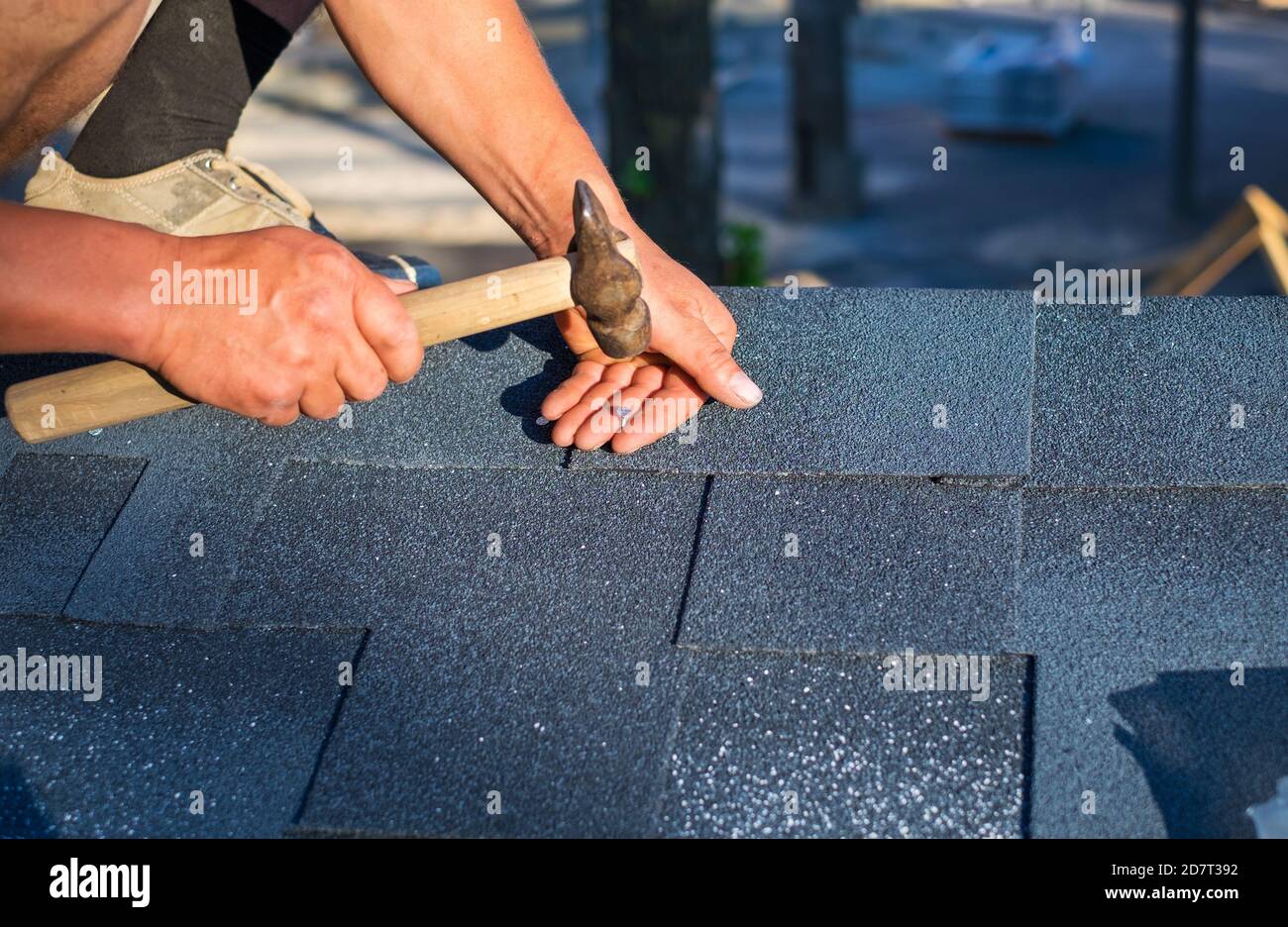 Worker repair corner bitumen roof shingles with hammer and nails Stock ...