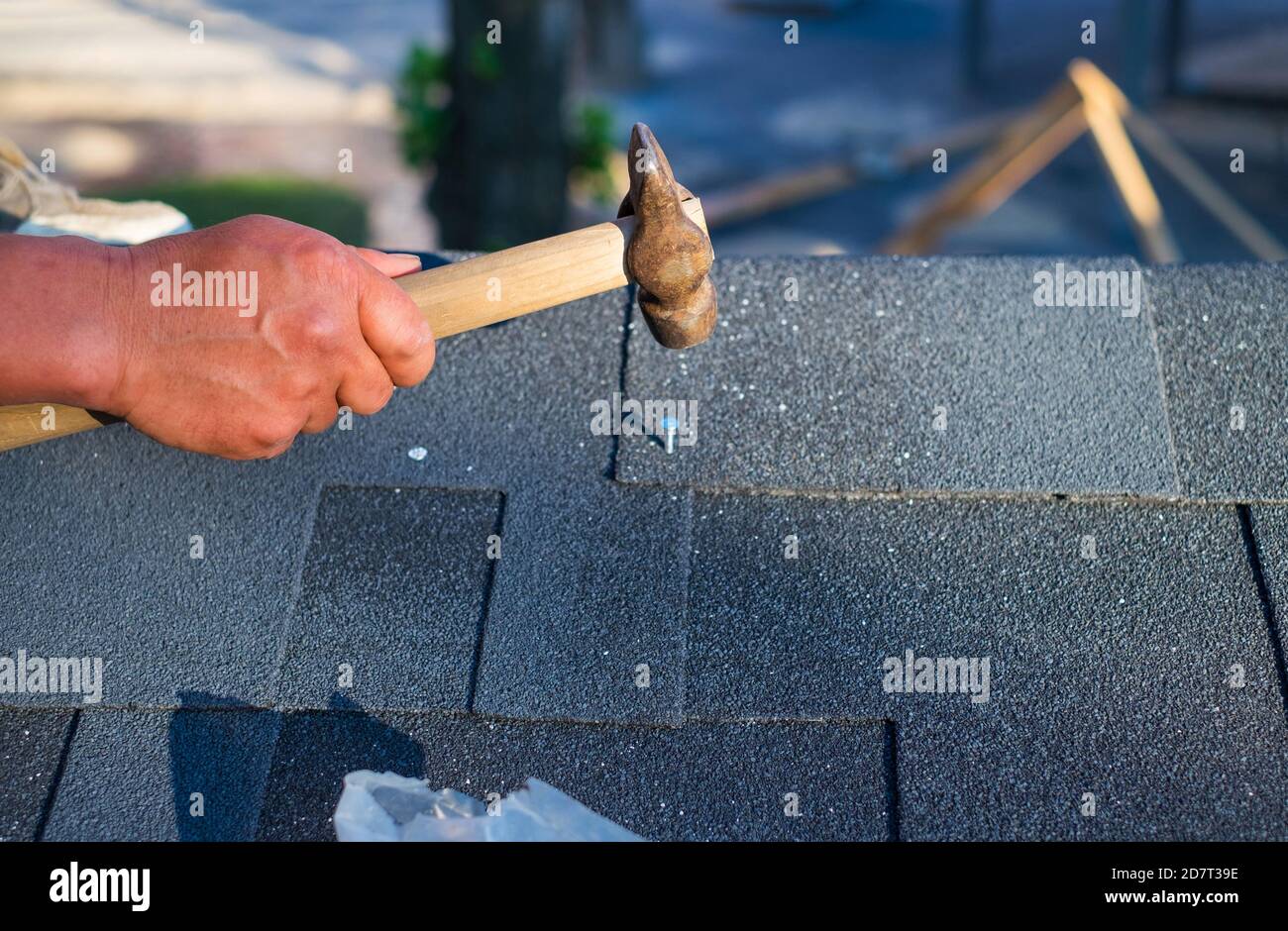 Contractor repair corner bitumen roof shingles with hammer and nails
