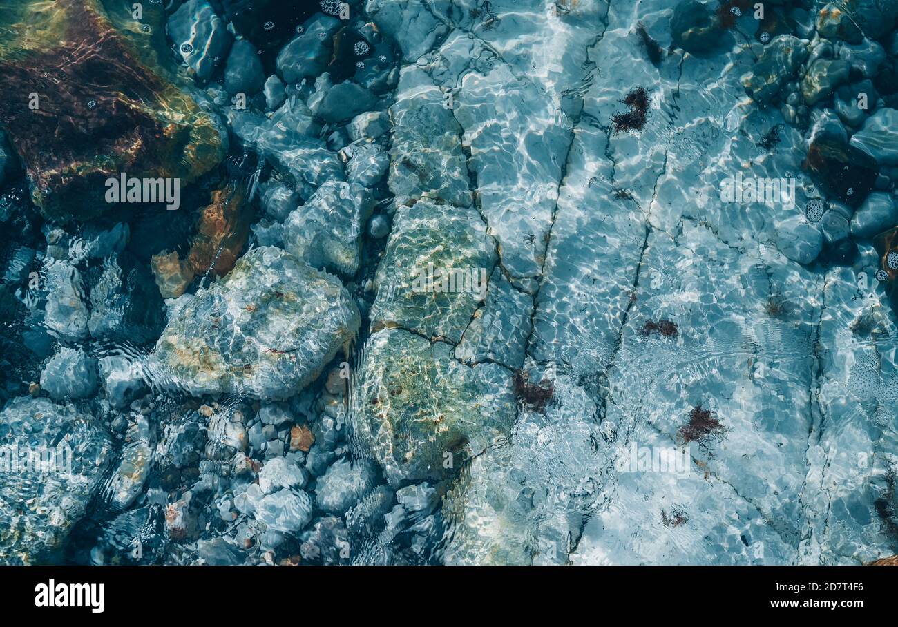 Top view of stones under transparent sea ocean blue clean water surface with refractions. Beautiful abstract natural background texture Stock Photo