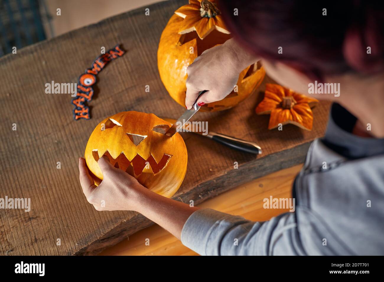 Woman carving Halloween pumpikn at home; Halloween pumpkin with a carved face Stock Photo