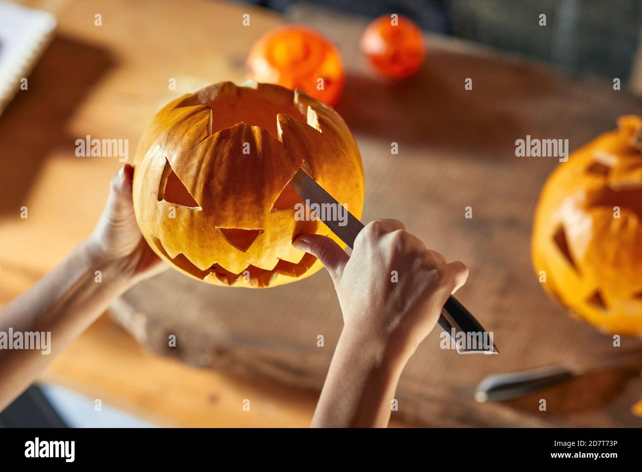 Woman carving Halloween pumpikn at home; Halloween pumpkin with a carved face Stock Photo