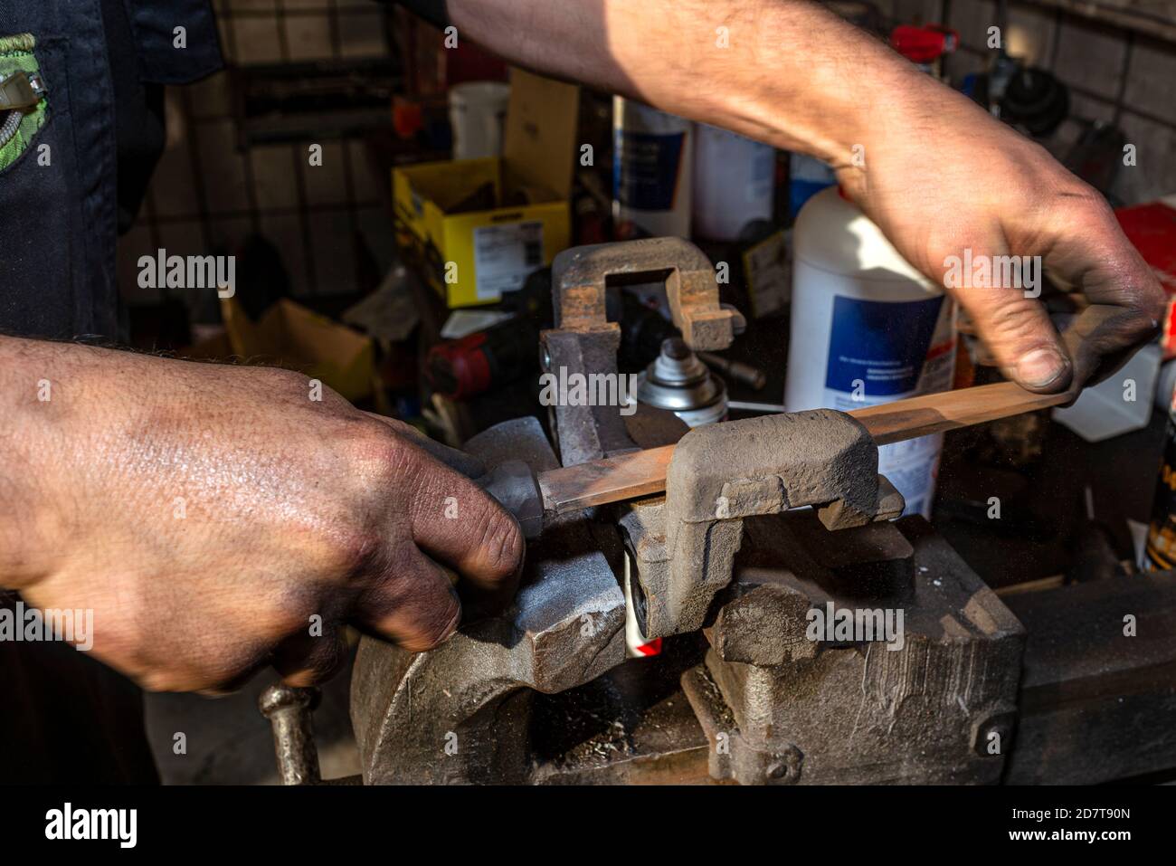 The mechanic uses a metal file to clean the rustcoated brake caliper