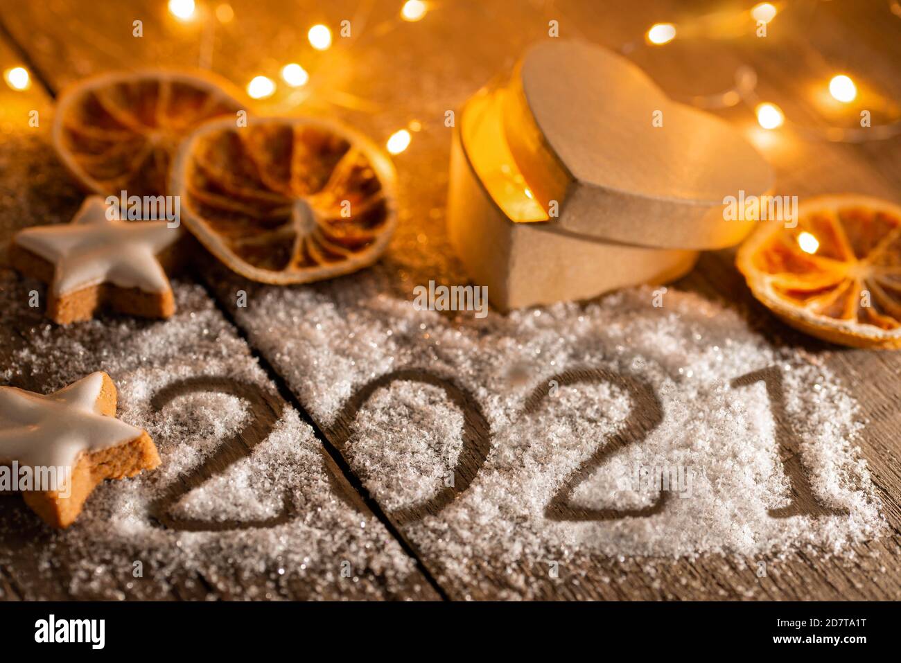 Jahreswechsel 2020/2021 - Jahreszahl auf Holz mit Lichtern, Gebäck und Weihnachtsdeko Stock Photo
