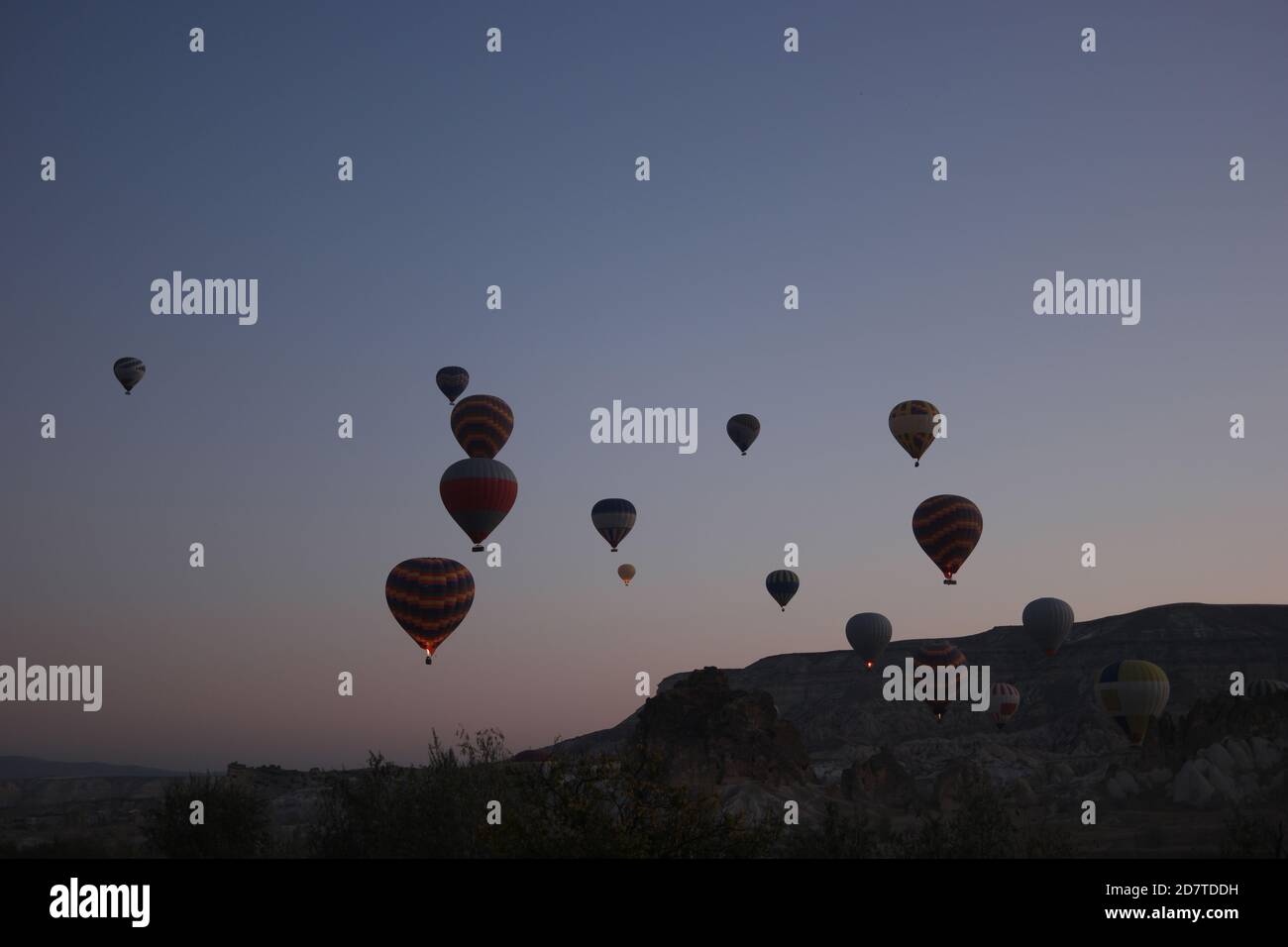 Colorful hot air balloons flying over rocky landscape at sunset sky ...