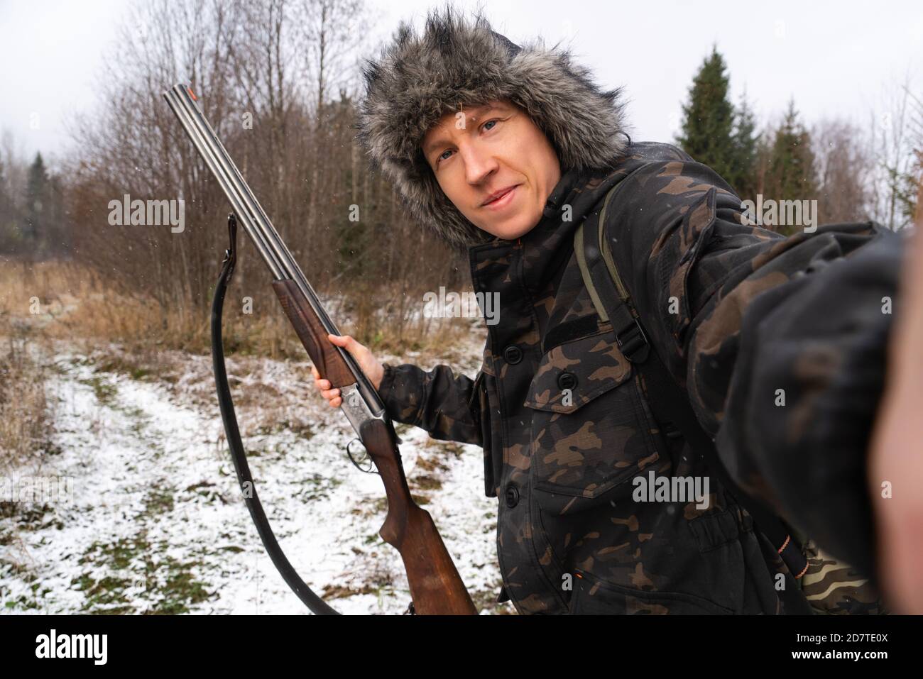 Hunter with a gun takes a selfie in the winter forest  Stock Photo