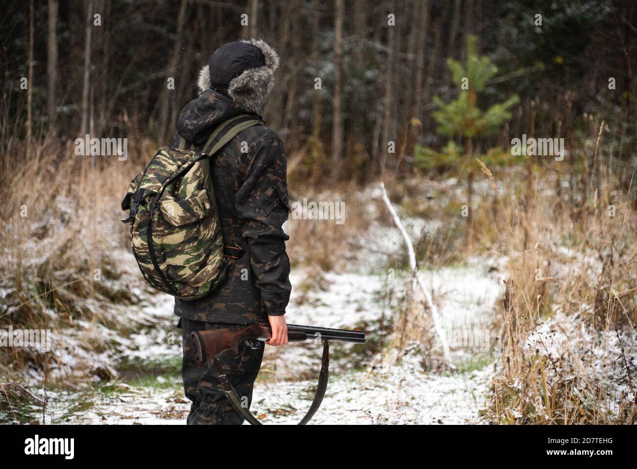 Hunter with a gun and a backpack in the winter forest Stock Photo