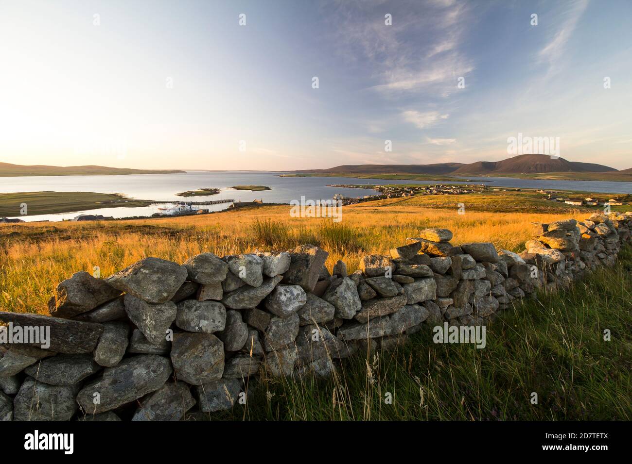 Sunrise above Stromness on Orkney islands with dry stone wall in the foreground and islands in the background Stock Photo