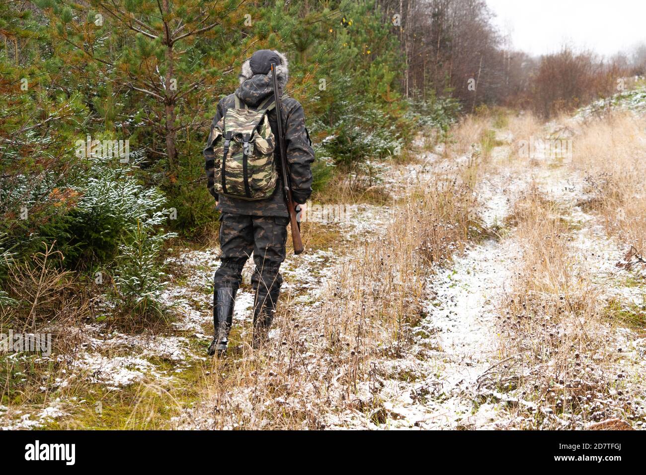 Hunter with a gun and a backpack in the winter forest Stock Photo