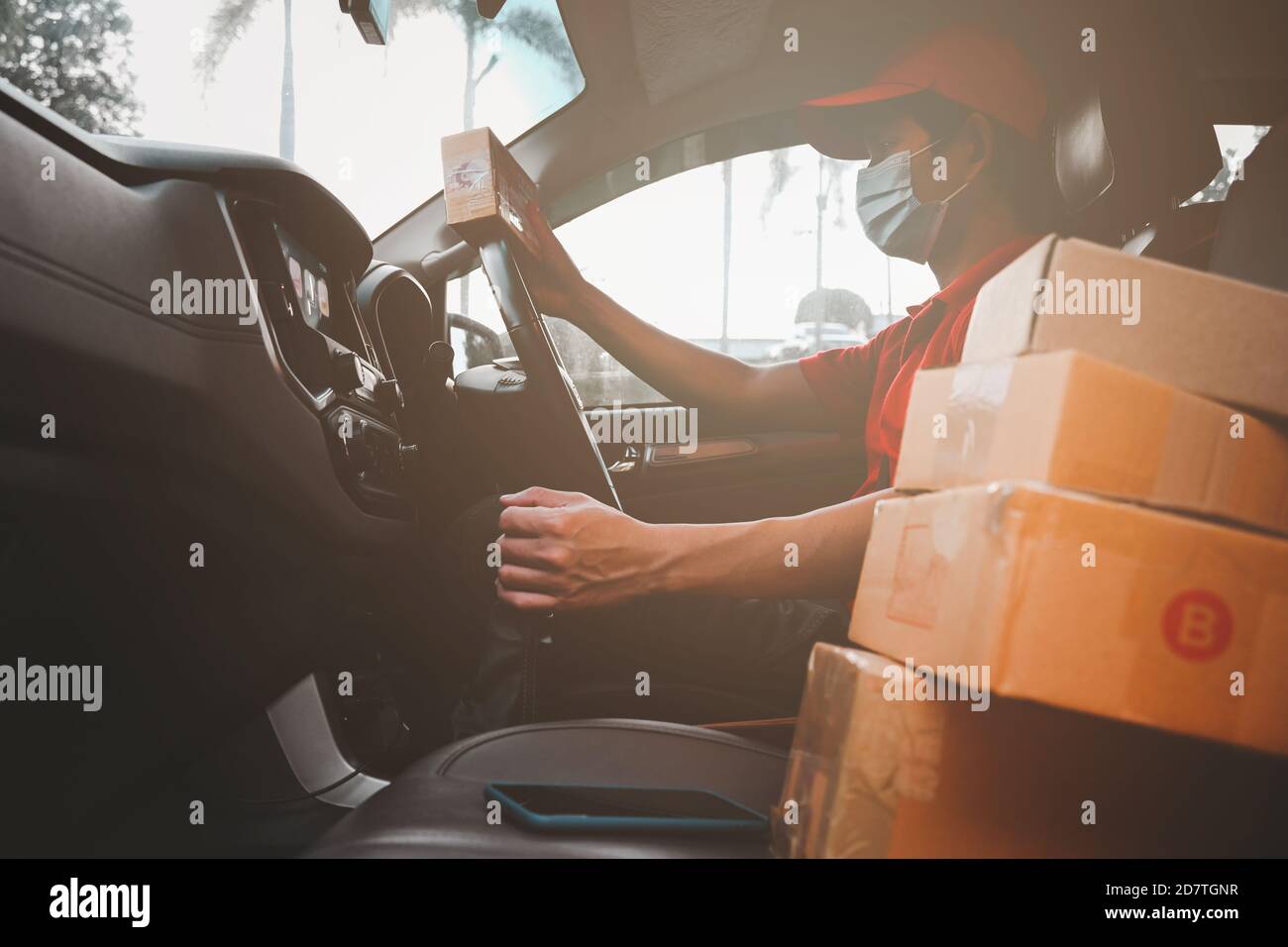 New normal express-Delivery services courier wearing medical mask for safety protection from virus infection working with postal boxes on delivery car Stock Photo