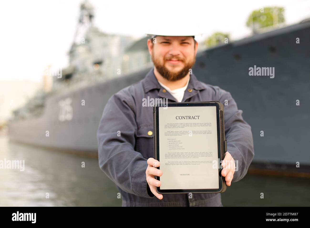 Focus on contract, captain showing document on tablet near vessel in background. Stock Photo