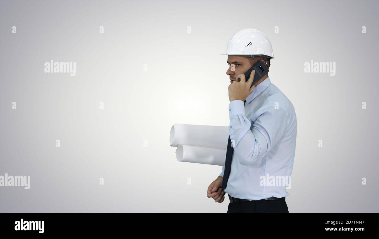 Engineer talking on phone with paperwork on gradient background. Stock Photo