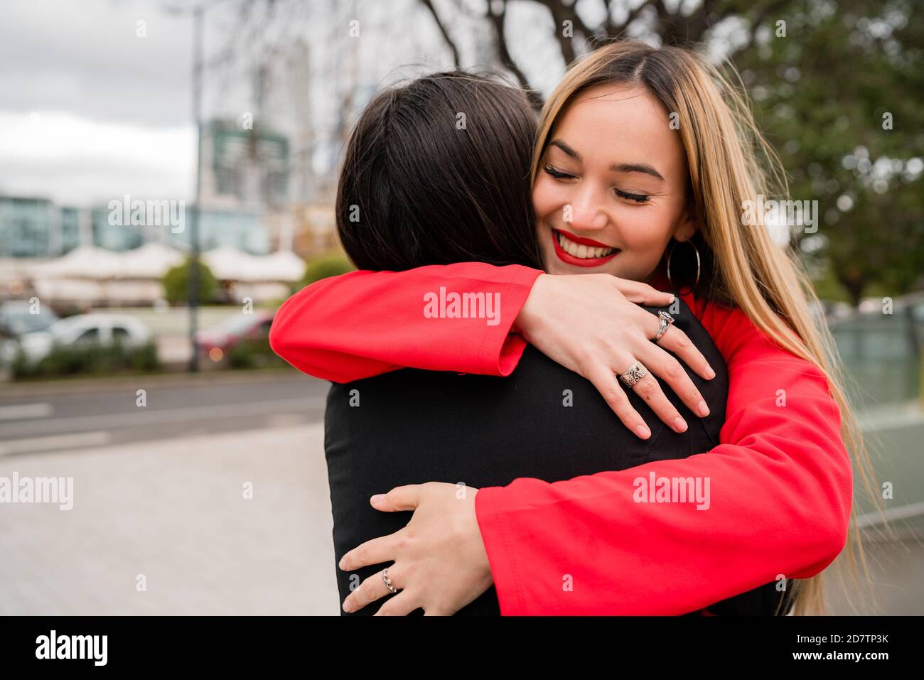 Portrait of two young friends hugging each other outdoors at the street ...