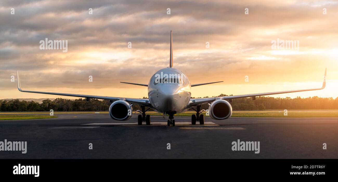 Sunset view of airplane on airport runway under dramatic sky in Hobart,Tasmania, Australia. Aviation technology and world travel concept. Stock Photo