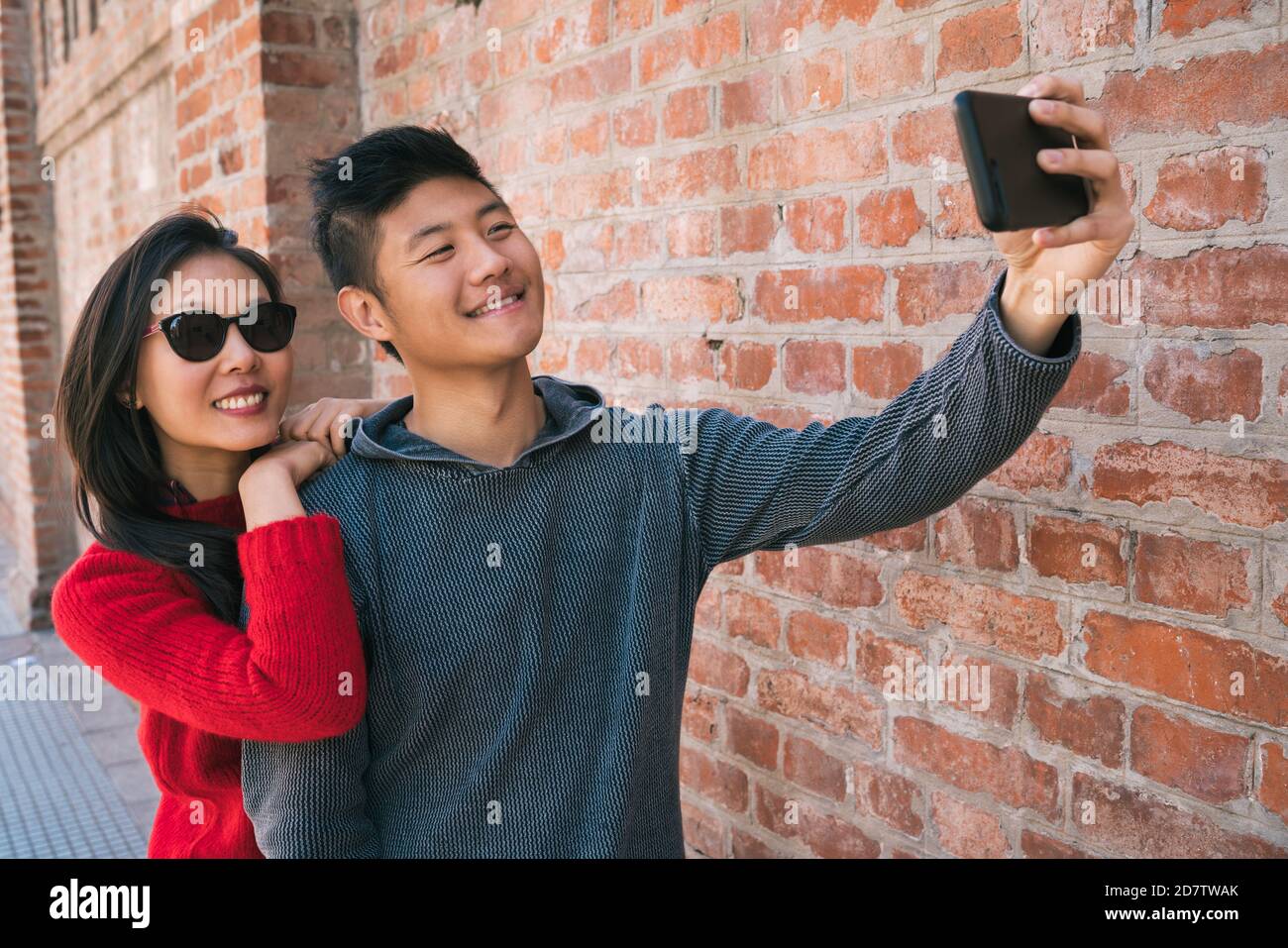 Portrait of a lovely asian couple taking a selfie with mobile phone ...