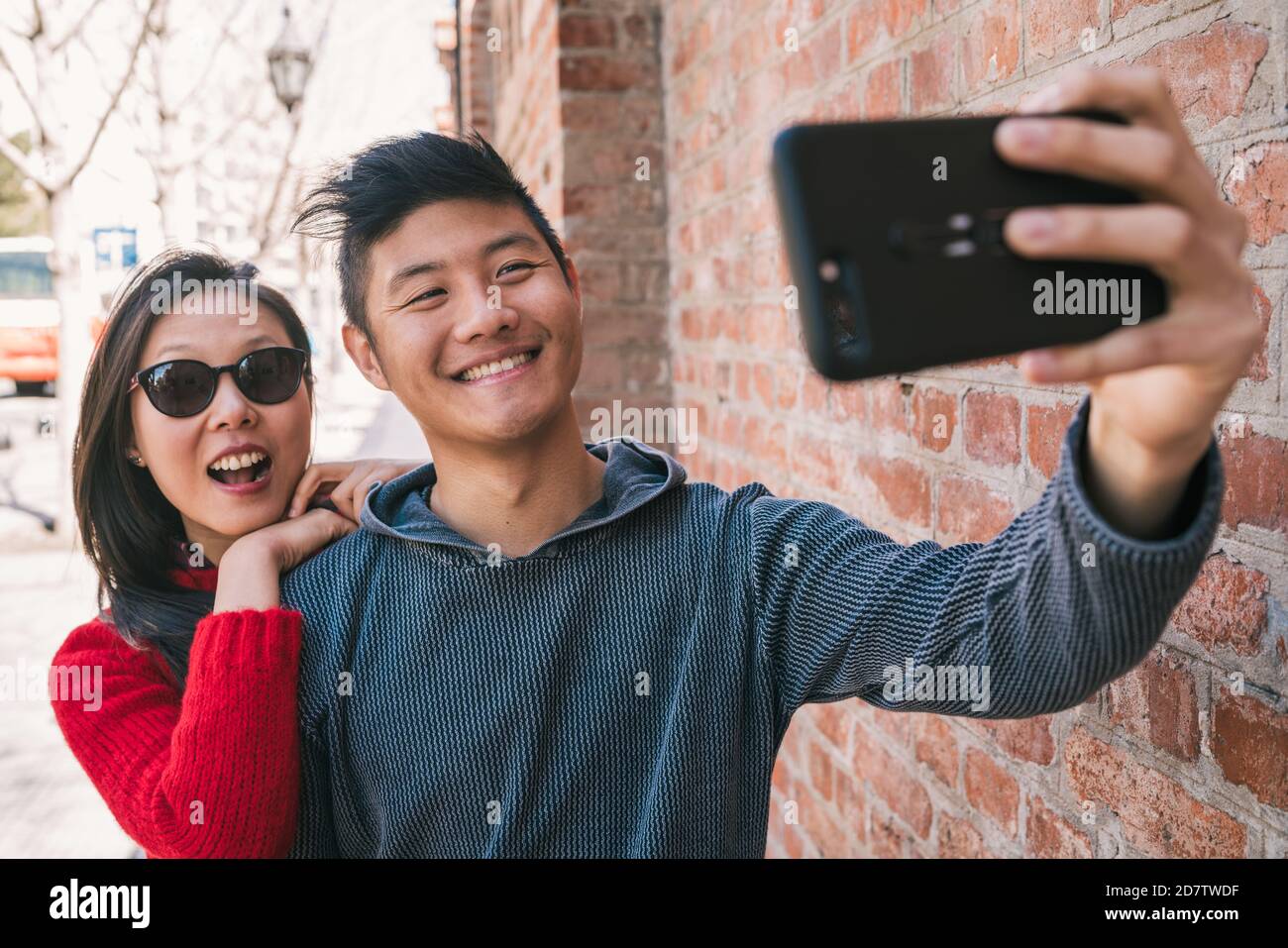 Portrait of a lovely asian couple taking a selfie with mobile phone ...