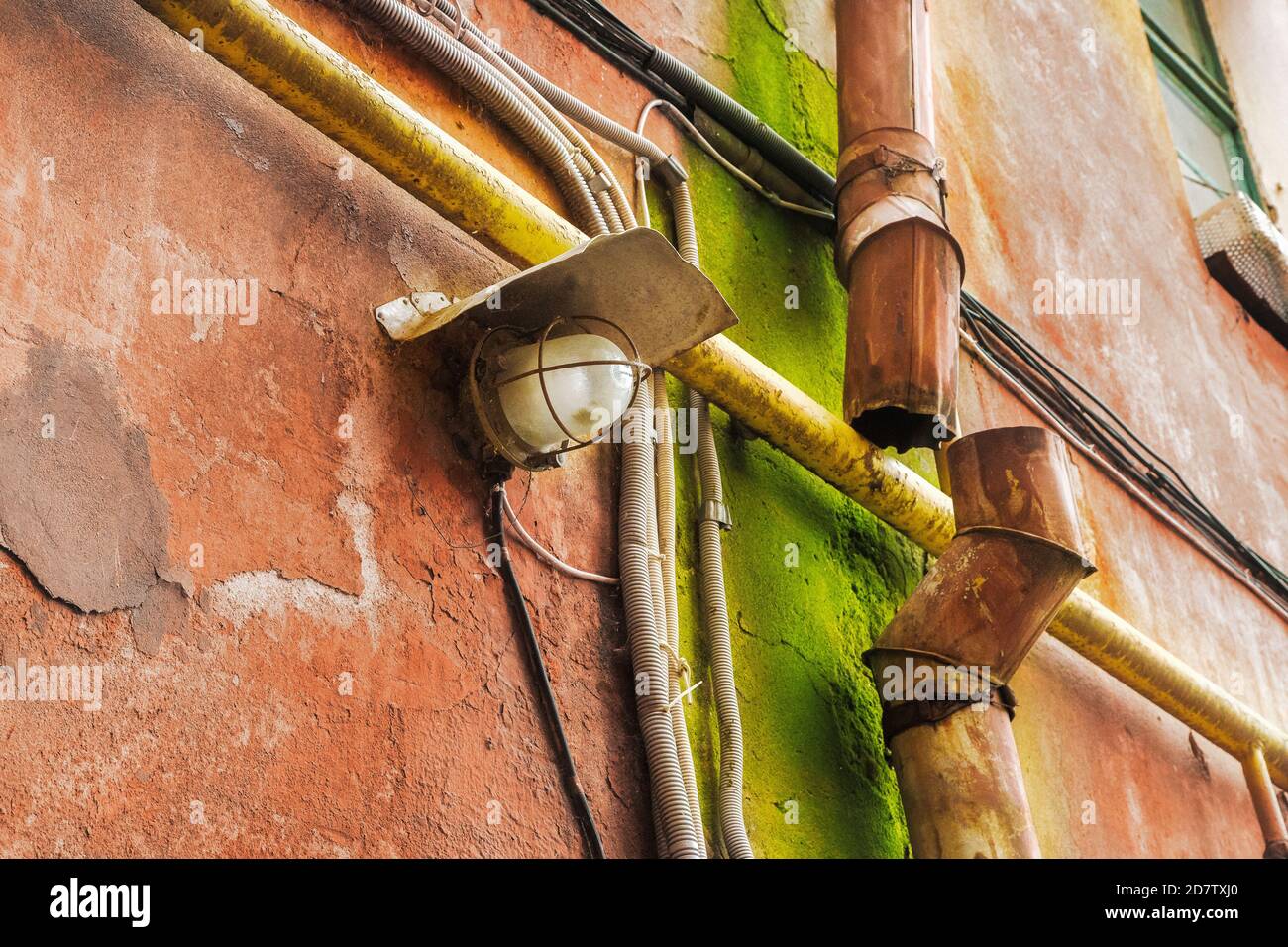 image of a lantern and a rusty drainpipe on the wall of a house Stock Photo