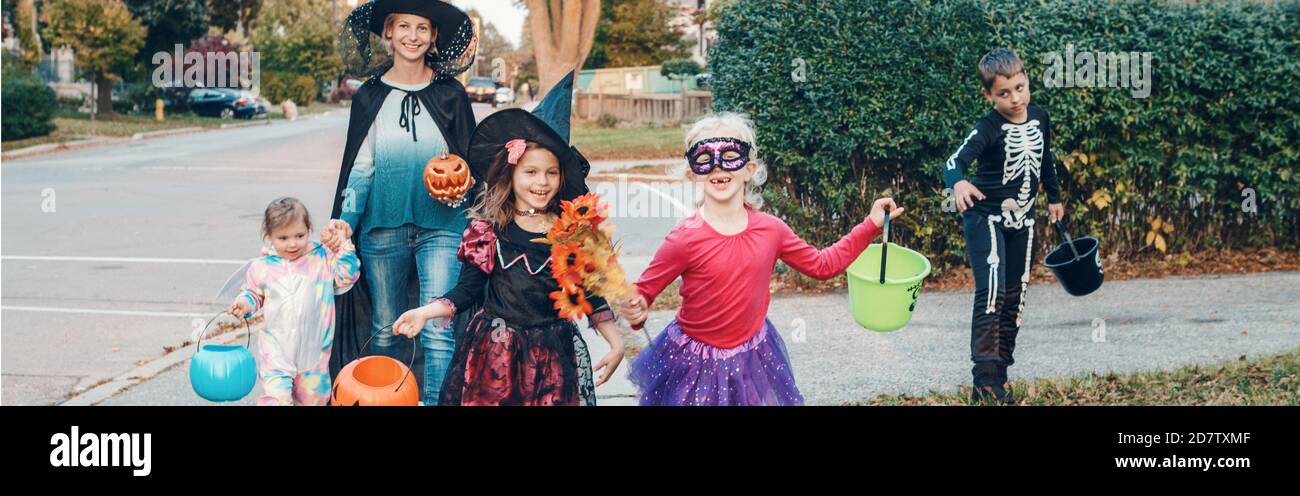 Trick or treat. Mother with children going to trick or treat on Halloween. Mom with kids in party costumes with baskets going to neighbourhood houses Stock Photo
