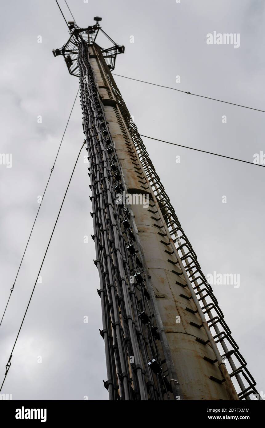 High metal pipe with cable routes, antennas and steps against cloudy