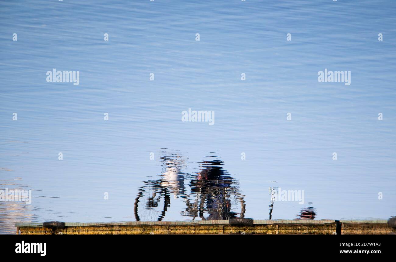 Reflection of a bicycle parked on a platoon pier on a lake, on a sunny day Stock Photo