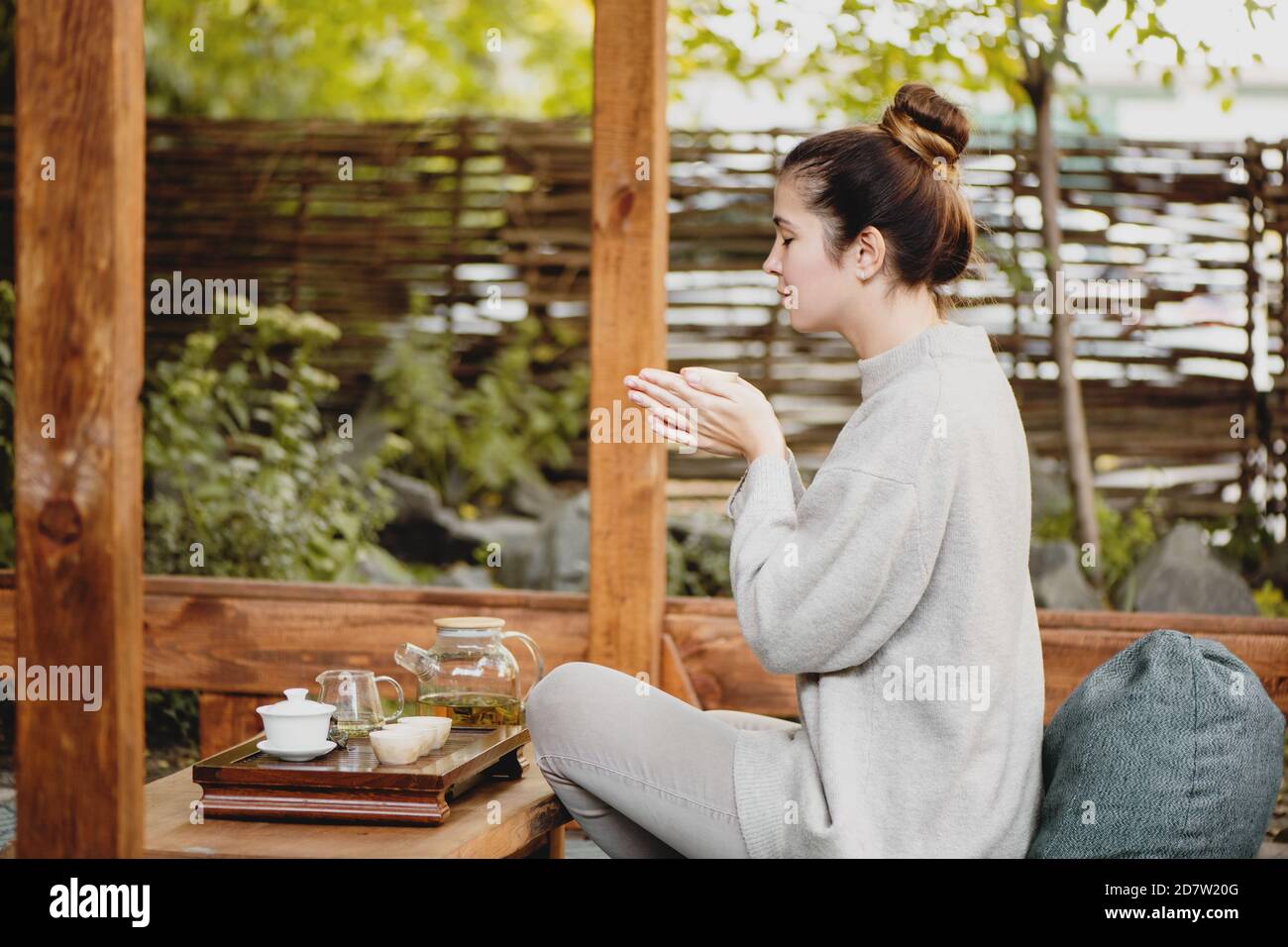 Side view of beautiful woman drinking chinese tea outside. Stock Photo